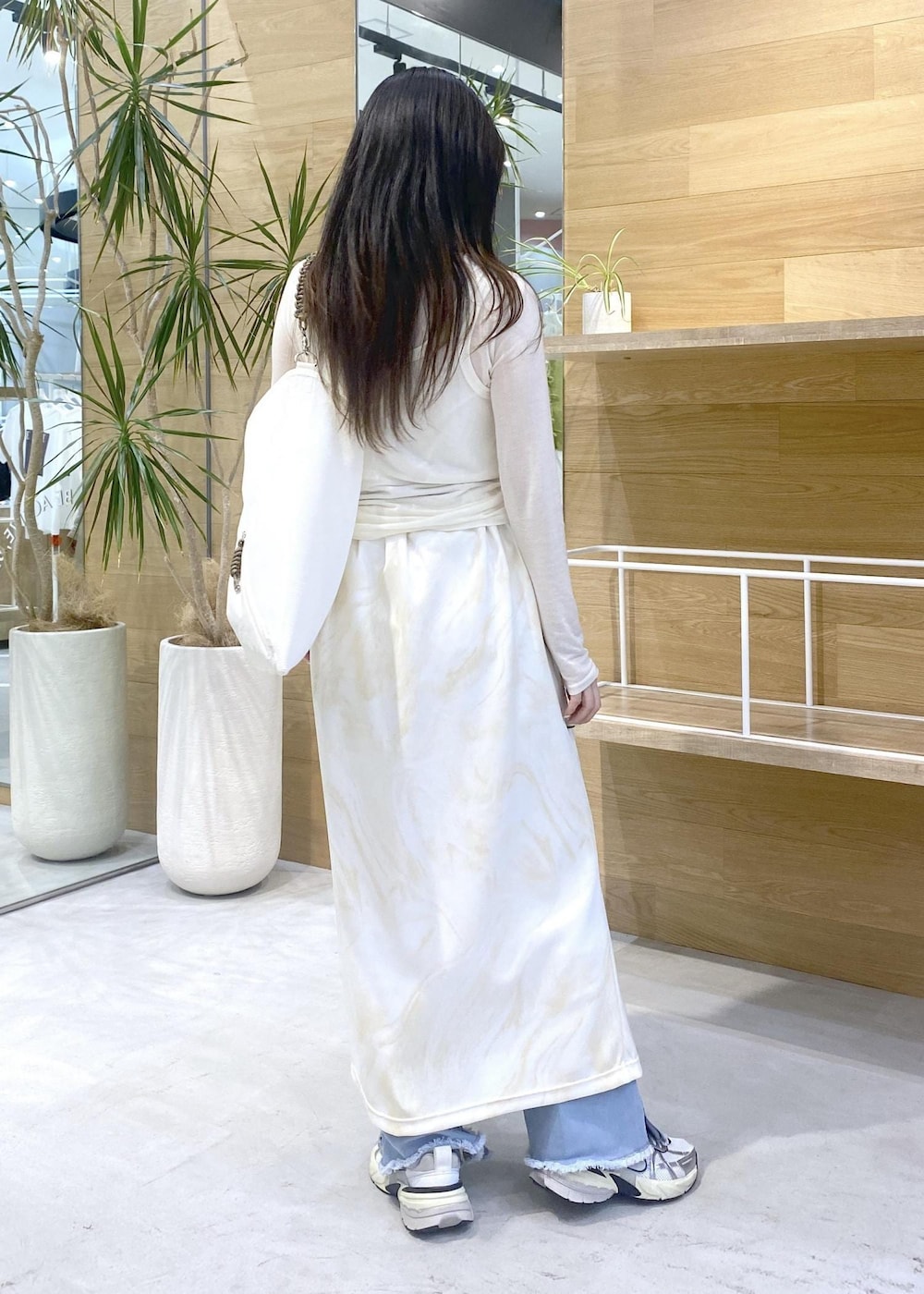 イエロー系のスカート、ホワイト系のアンサンブル、ブルー系のデニムパンツを着用したレディースの秋コーディネートの4枚目の写真