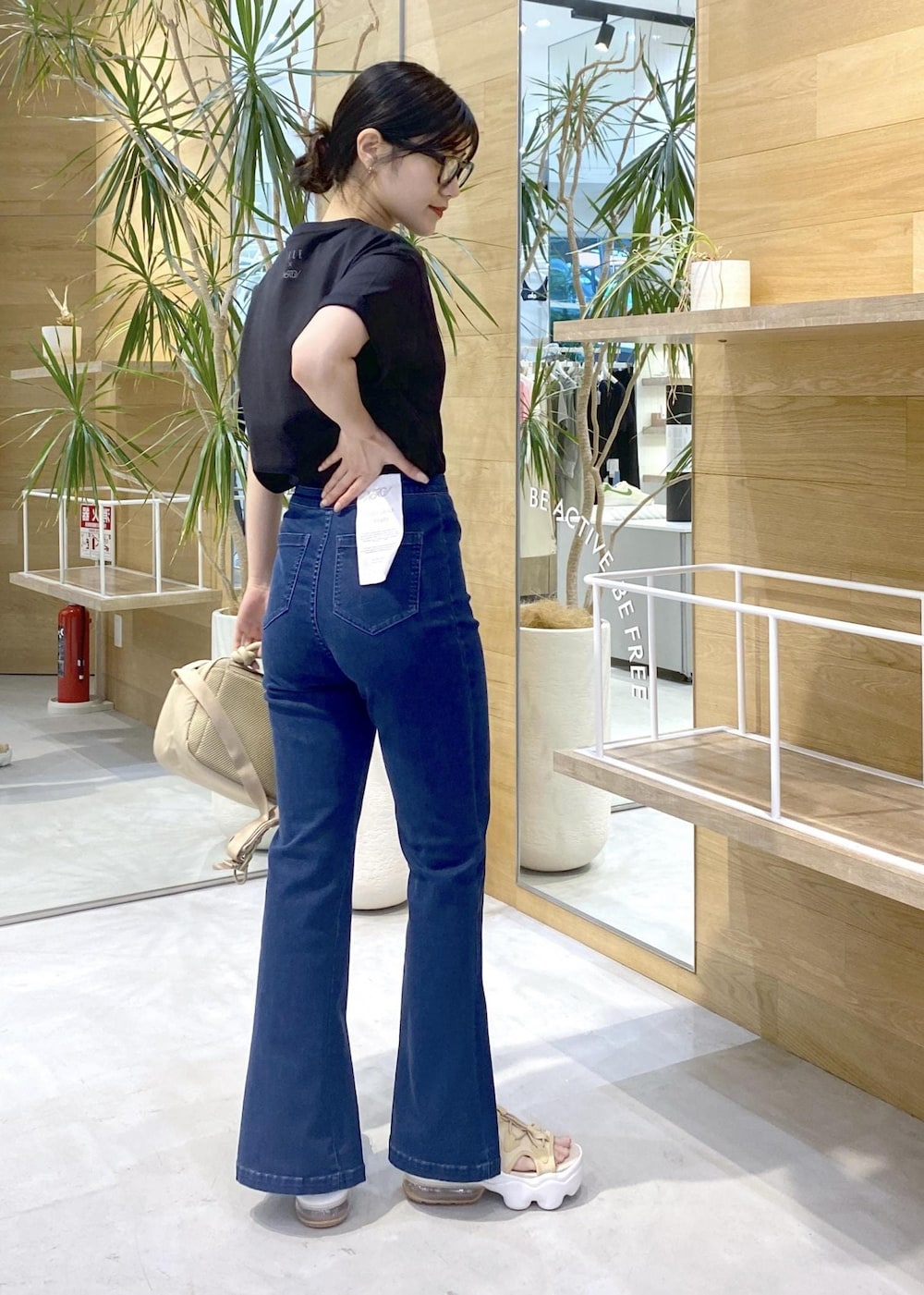 ブルー系のデニムパンツ、ベージュ系のサンダル、ブラック系のTシャツ/カットソーを着用したレディースの夏コーディネートの4枚目の写真