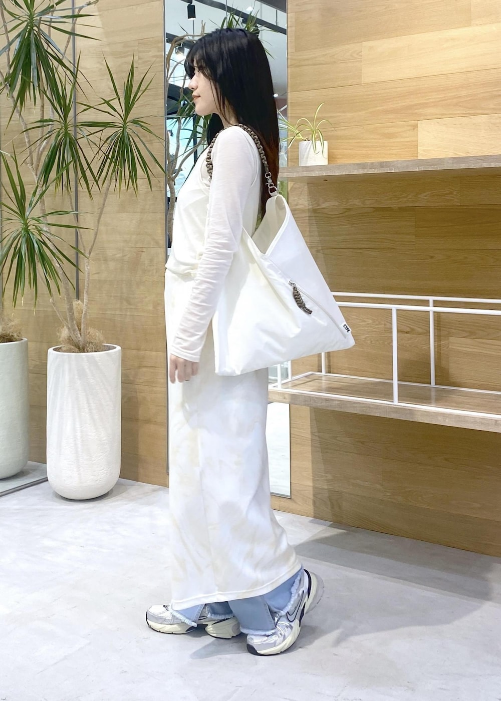 イエロー系のスカート、ホワイト系のアンサンブル、ブルー系のデニムパンツを着用したレディースの秋コーディネートの3枚目の写真