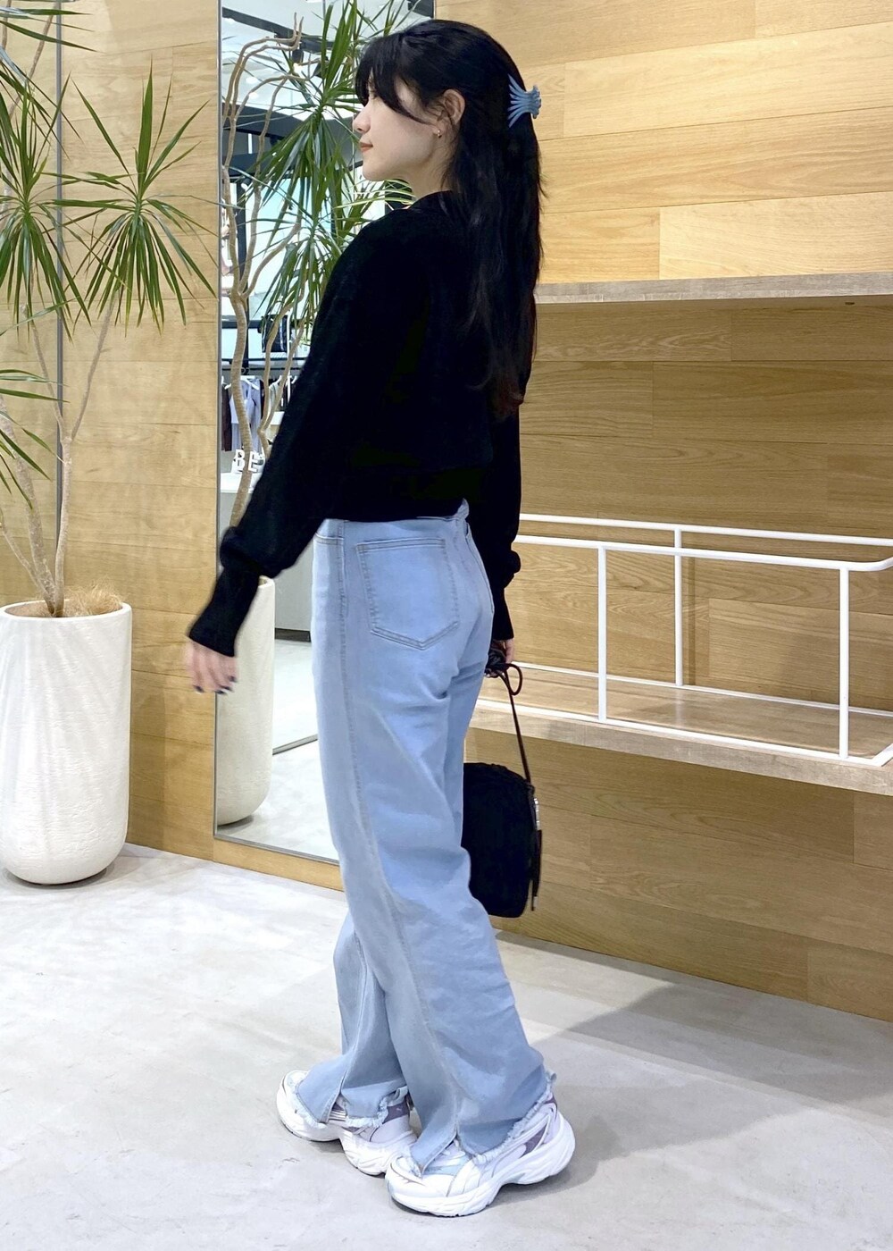 ブルー系のデニムパンツ、ブラック系のショルダーバッグ、ブラック系のカーディガン/ボレロを着用したレディースの秋コーディネートの3枚目の写真