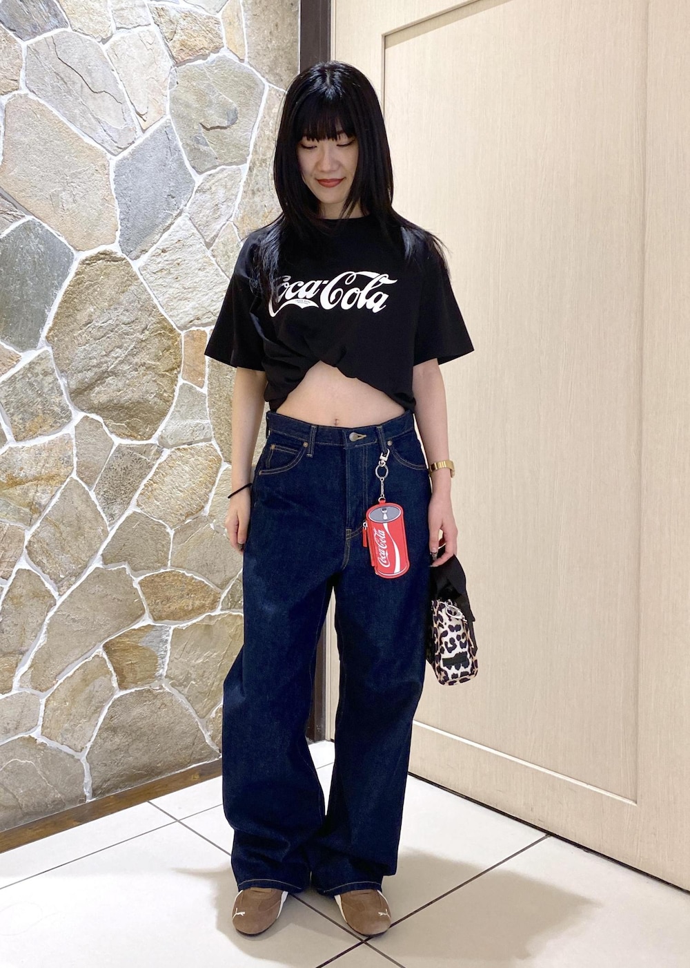 ベージュ系のスニーカー、ブルー系のデニムパンツ、ベージュ系のショルダーバッグを着用したレディースの夏コーディネートの2枚目の写真