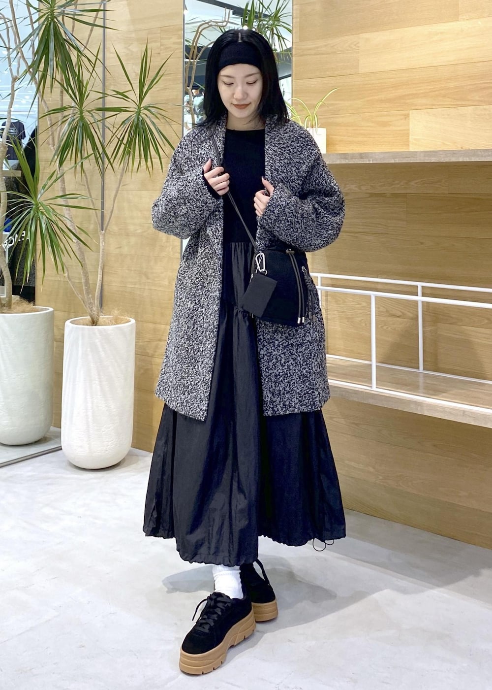 ブラック系のショルダーバッグ、ブラック系のワンピース、ブラック系のチェスターコートを着用したレディースの秋コーディネートの6枚目の写真