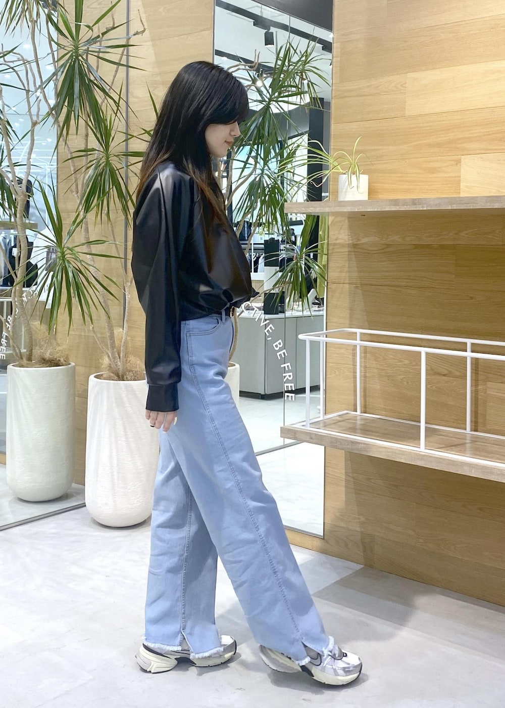 ブラック系のその他トップス、ブルー系のデニムパンツ、ホワイト系のスニーカーを着用したレディースの秋コーディネートの6枚目の写真