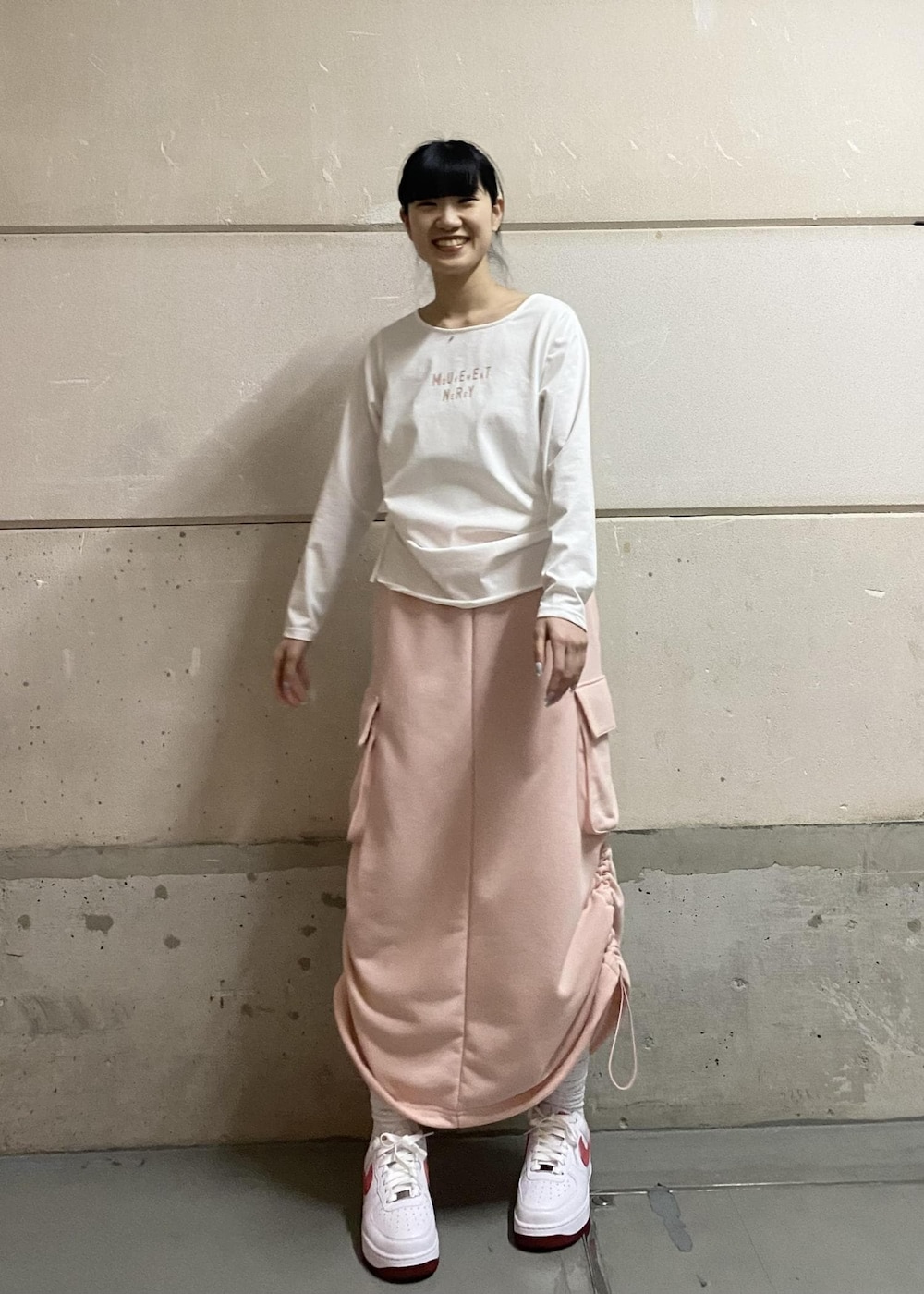 ピンク系のスカート、ホワイト系のTシャツ/カットソー、ホワイト系のスニーカーを着用したレディースの冬コーディネートの2枚目の写真