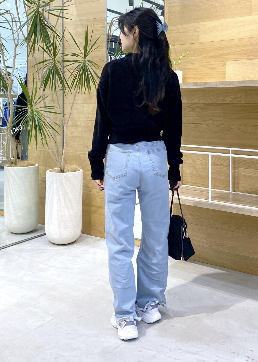 ブルー系のデニムパンツ、ブラック系のショルダーバッグ、ブラック系のカーディガン/ボレロを着用したレディースの秋コーディネートの4枚目の写真