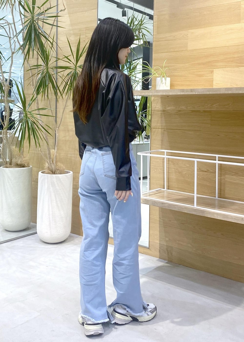 ブラック系のその他トップス、ブルー系のデニムパンツ、ホワイト系のスニーカーを着用したレディースの秋コーディネートの5枚目の写真