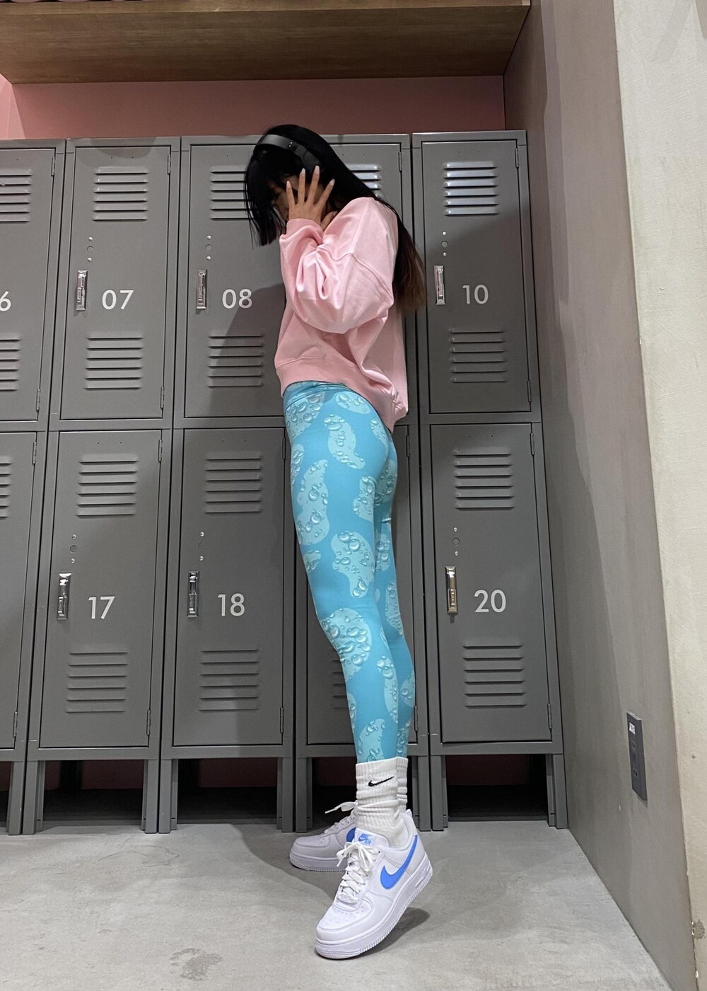 ピンク系のスウェット、ホワイト系のスニーカー、ブルー系のレギンス/スパッツを着用したレディースの冬コーディネートの2枚目の写真