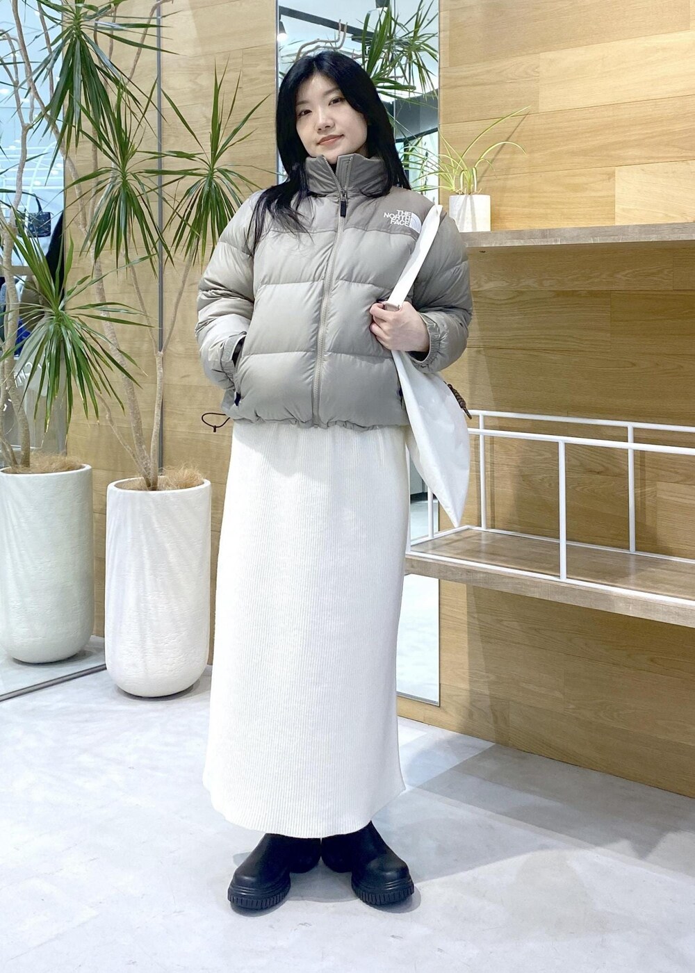 ホワイト系のトートバッグ、ベージュ系のダウンジャケット/コートを着用したレディースの秋コーディネートの2枚目の写真