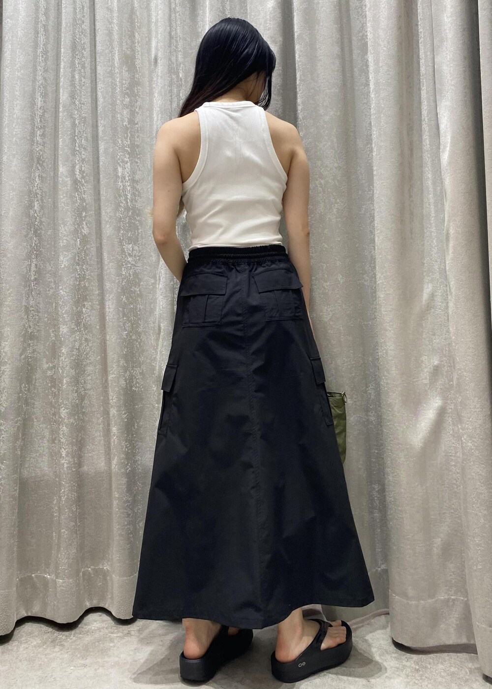 ブラック系のサンダル、ブラック系のスカート、ホワイト系のタンクトップを着用したレディースの春コーディネートの5枚目の写真