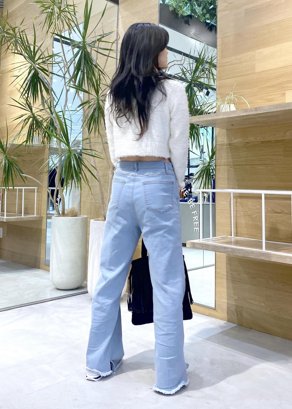 ホワイト系のスニーカー、ブルー系のデニムパンツ、ブラック系のトートバッグを着用したレディースの秋コーディネートの5枚目の写真