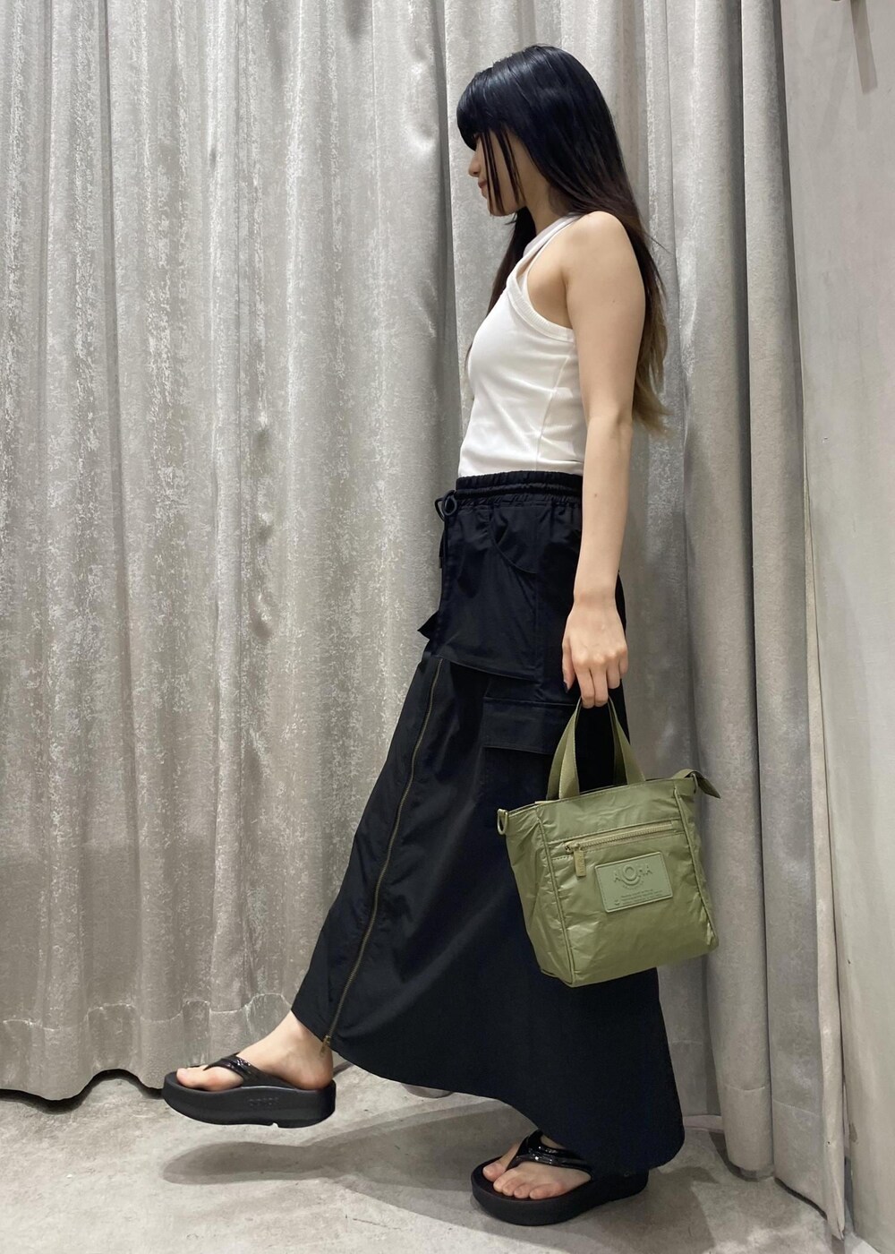 ブラック系のサンダル、ブラック系のスカート、ホワイト系のタンクトップを着用したレディースの春コーディネートの3枚目の写真