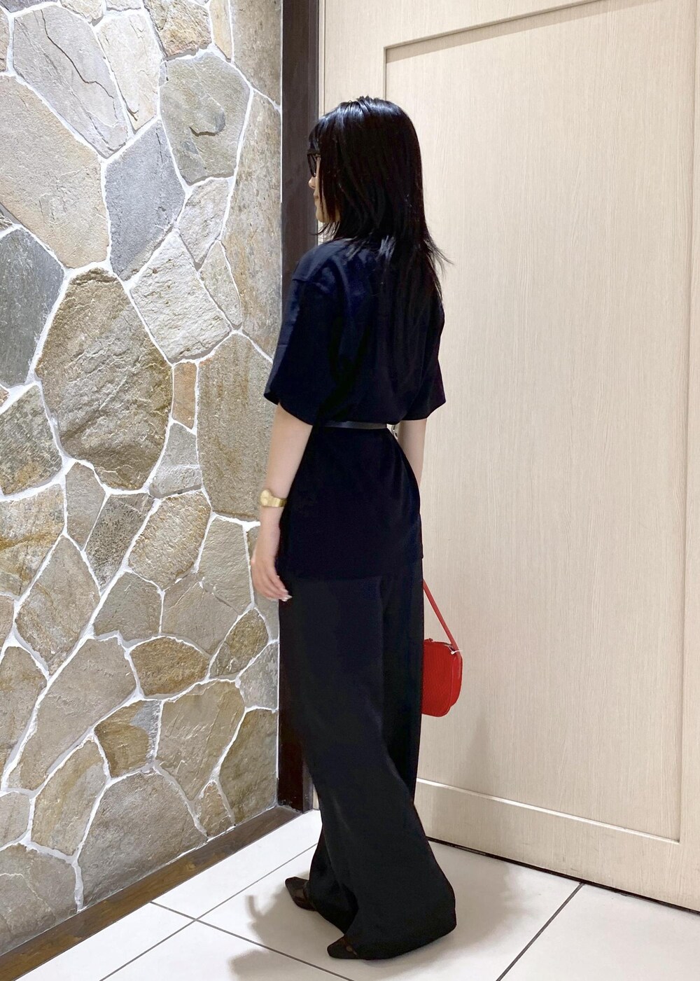 ブラック系のパンプス、ブラック系のスラックス、レッド系のハンドバッグを着用したレディースの夏コーディネートの5枚目の写真