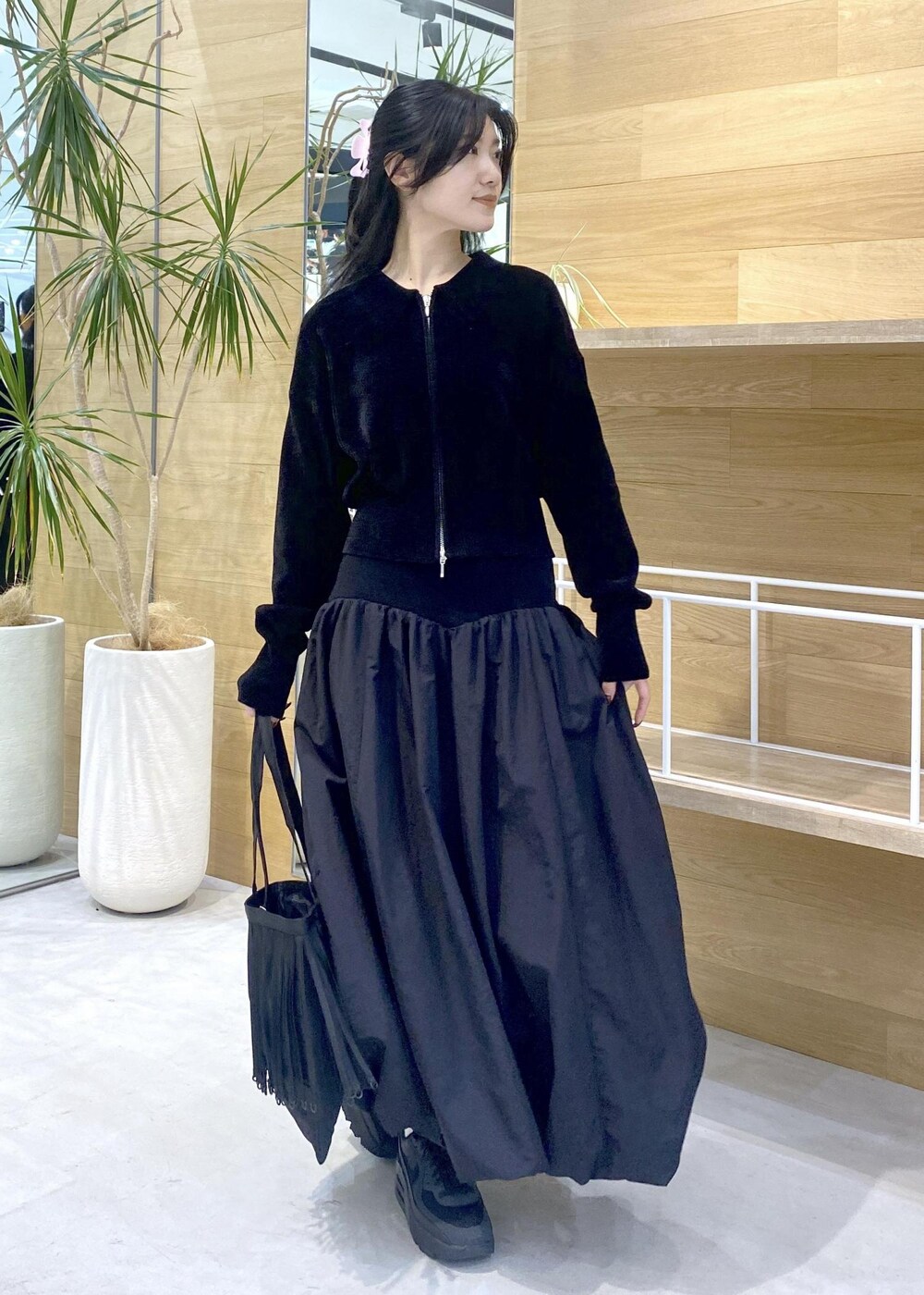 ブラック系のスカート、ブラック系のカーディガン/ボレロ、ブラック系のスニーカーを着用したレディースの冬コーディネートの3枚目の写真