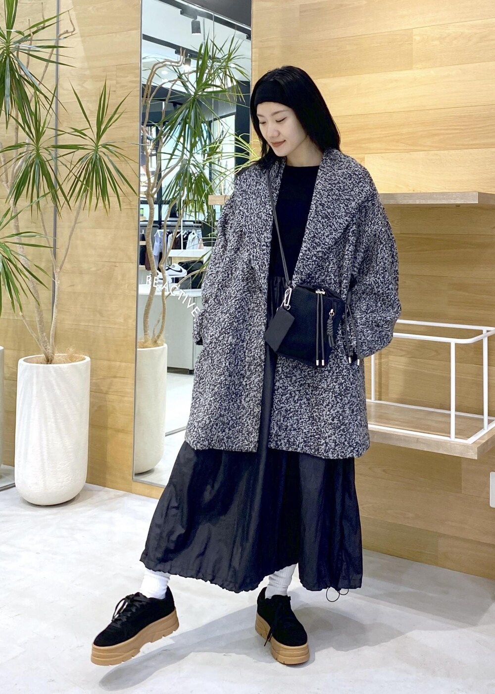 ブラック系のショルダーバッグ、ブラック系のワンピース、ブラック系のチェスターコートを着用したレディースの秋コーディネートの3枚目の写真