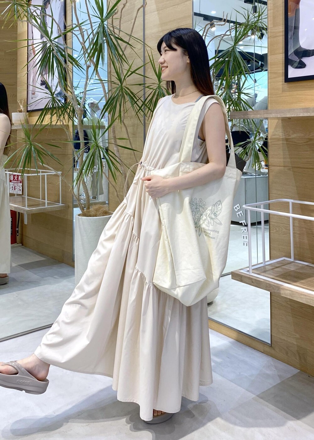 ベージュ系のサンダル、ホワイト系のトートバッグ、ホワイト系のワンピースを着用したレディースの夏コーディネートの2枚目の写真