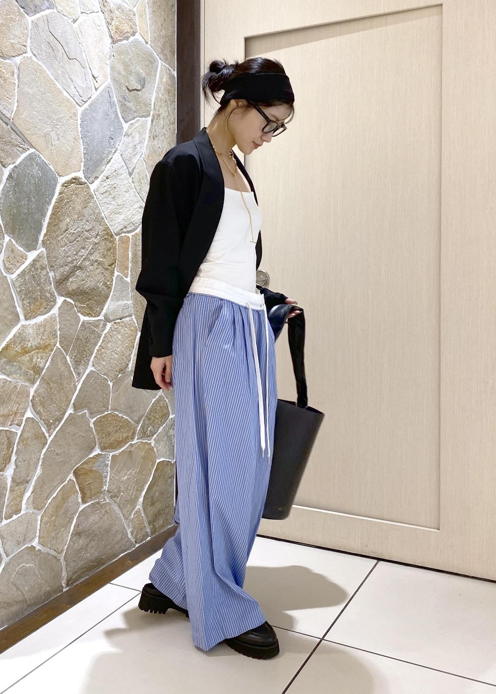 ブルー系のスラックス、ブラック系のテーラードジャケット、ブラック系のローファーを着用したレディースの秋コーディネートの5枚目の写真