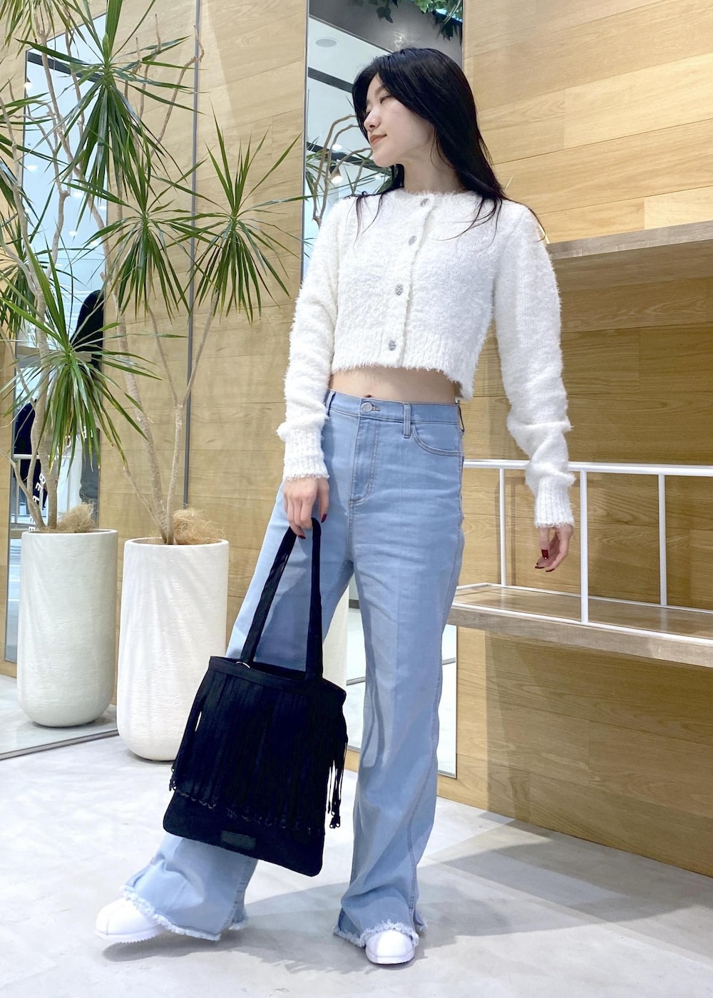 ホワイト系のスニーカー、ブルー系のデニムパンツ、ブラック系のトートバッグを着用したレディースの秋コーディネートの2枚目の写真