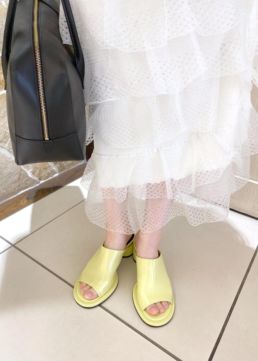 グリーン系のサンダル、ホワイト系のスカート、ブラック系のボストンバッグを着用したレディースの夏コーディネートの7枚目の写真