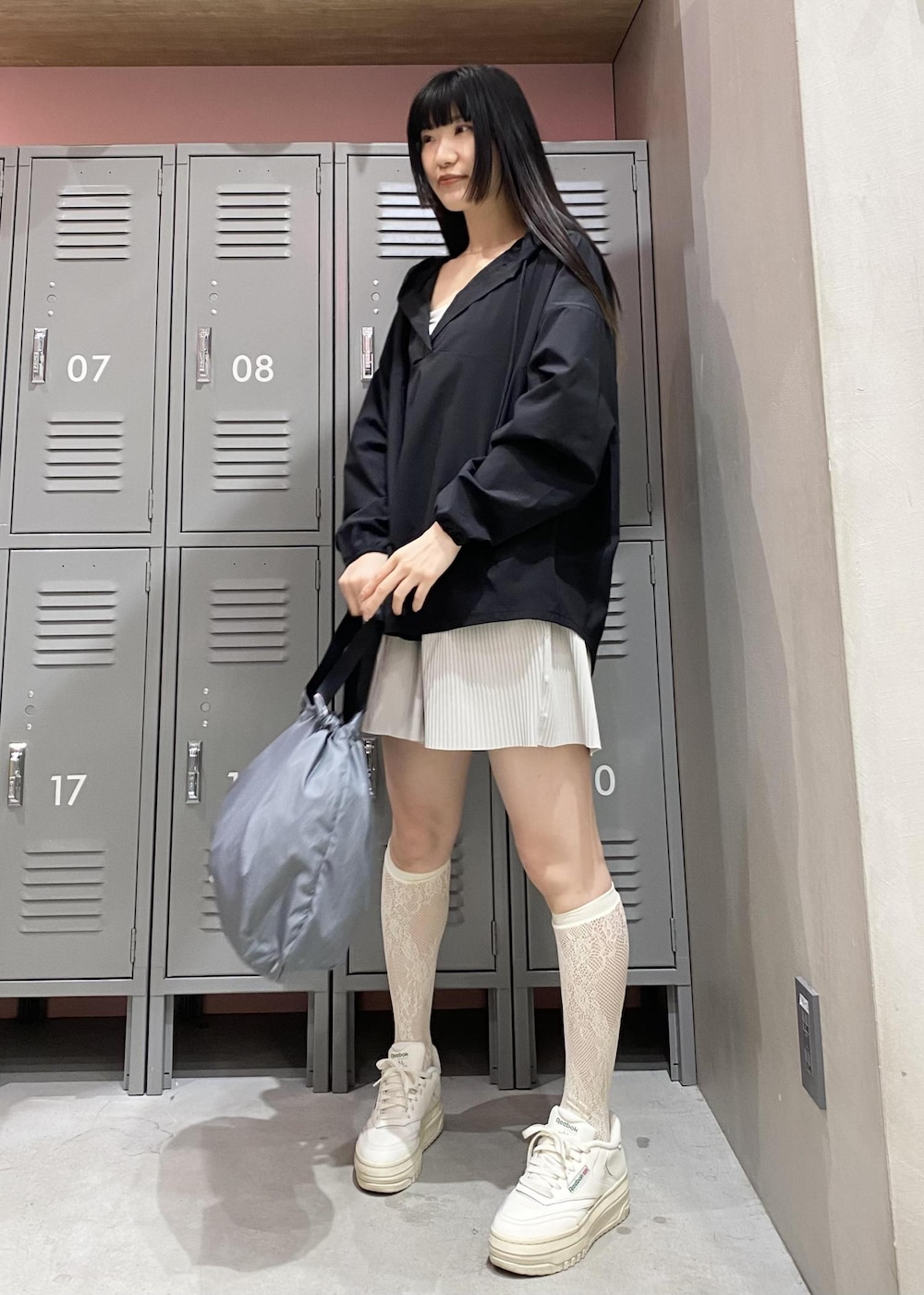 ホワイト系のスニーカー、グレー系のハンドバッグ、ブラック系のパーカーを着用したレディースの春コーディネートの2枚目の写真