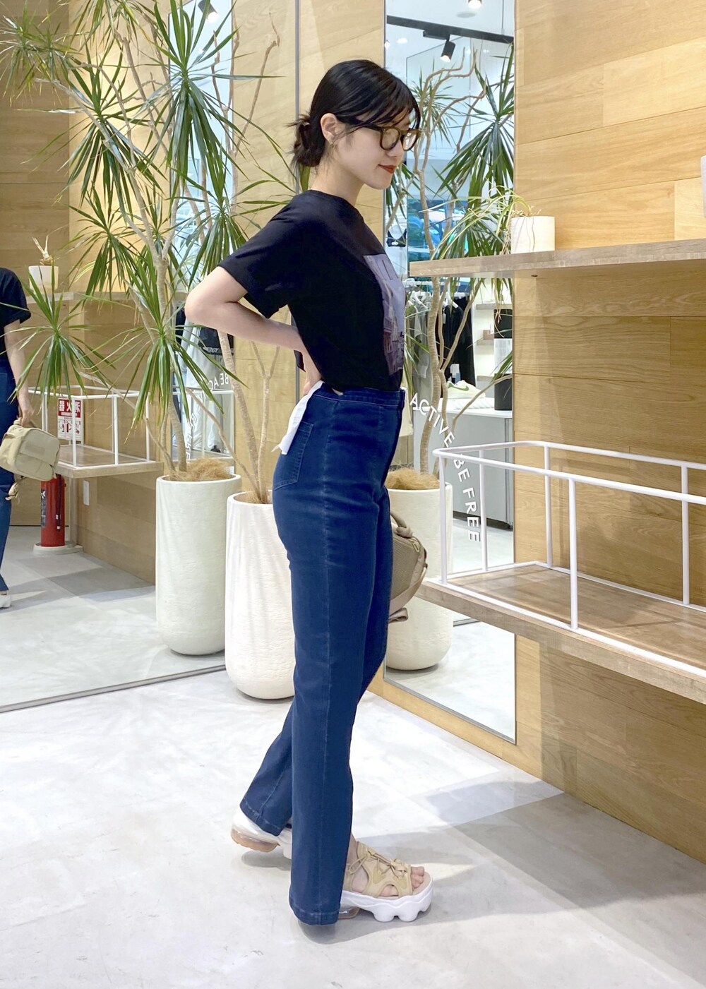 ブルー系のデニムパンツ、ベージュ系のサンダル、ブラック系のTシャツ/カットソーを着用したレディースの夏コーディネートの3枚目の写真