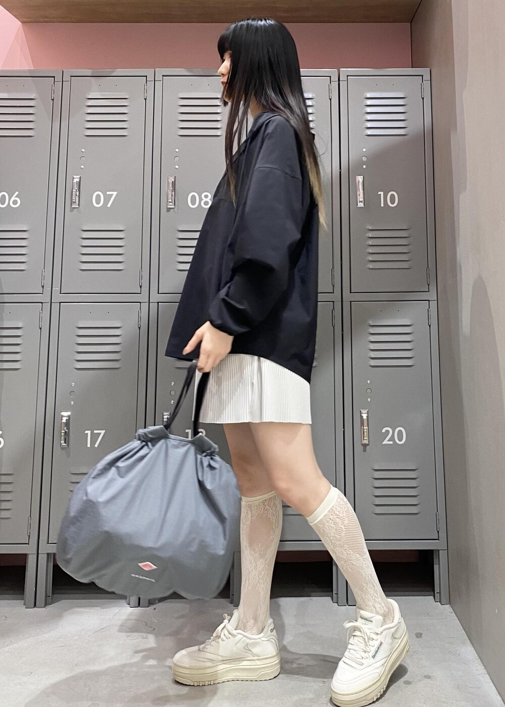 ホワイト系のスニーカー、グレー系のハンドバッグ、ブラック系のパーカーを着用したレディースの春コーディネートの3枚目の写真