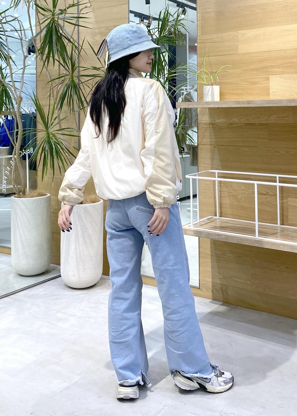 ホワイト系のスニーカー、ブルー系のデニムパンツ、ブルー系のハットを着用したレディースの秋コーディネートの5枚目の写真