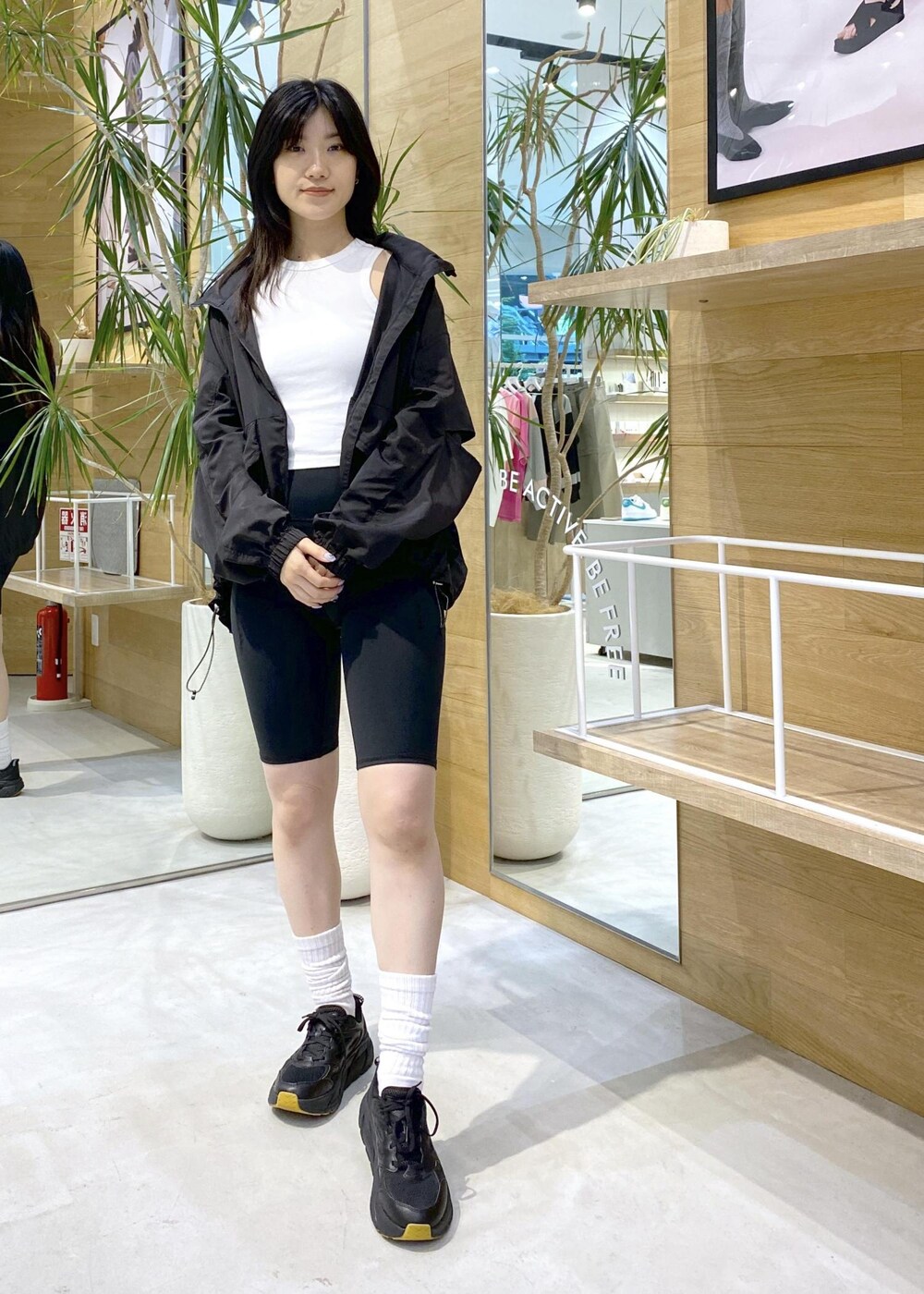 ブラック系のブルゾン、ホワイト系のタンクトップ、ブラック系のスニーカーを着用したレディースの夏コーディネートの2枚目の写真