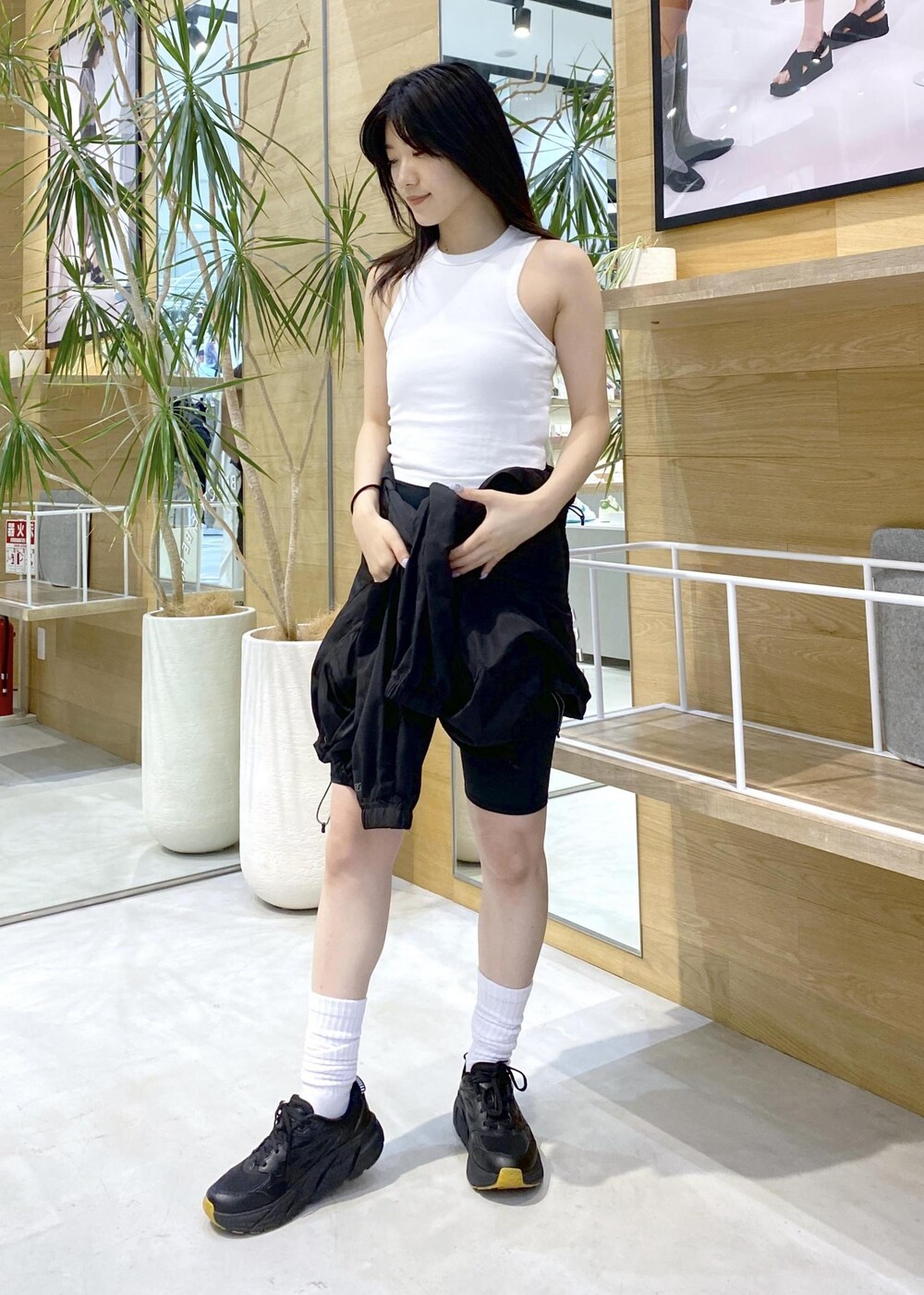 ブラック系のブルゾン、ホワイト系のタンクトップ、ブラック系のスニーカーを着用したレディースの夏コーディネートの5枚目の写真