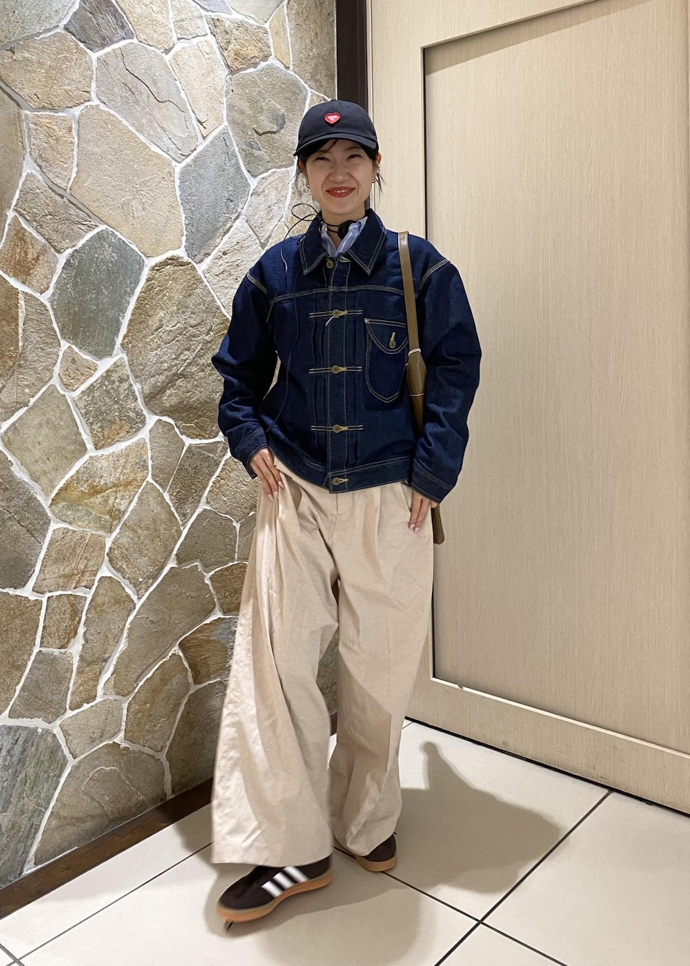 グリーン系のショルダーバッグ、ブルー系のデニムジャケット、ホワイト系のその他パンツを着用したレディースの冬コーディネートの2枚目の写真