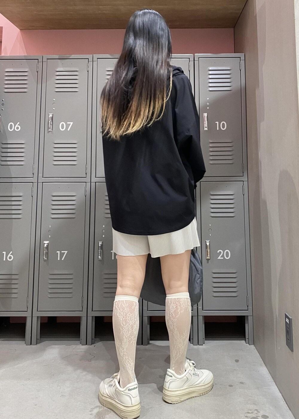 ホワイト系のスニーカー、グレー系のハンドバッグ、ブラック系のパーカーを着用したレディースの春コーディネートの4枚目の写真