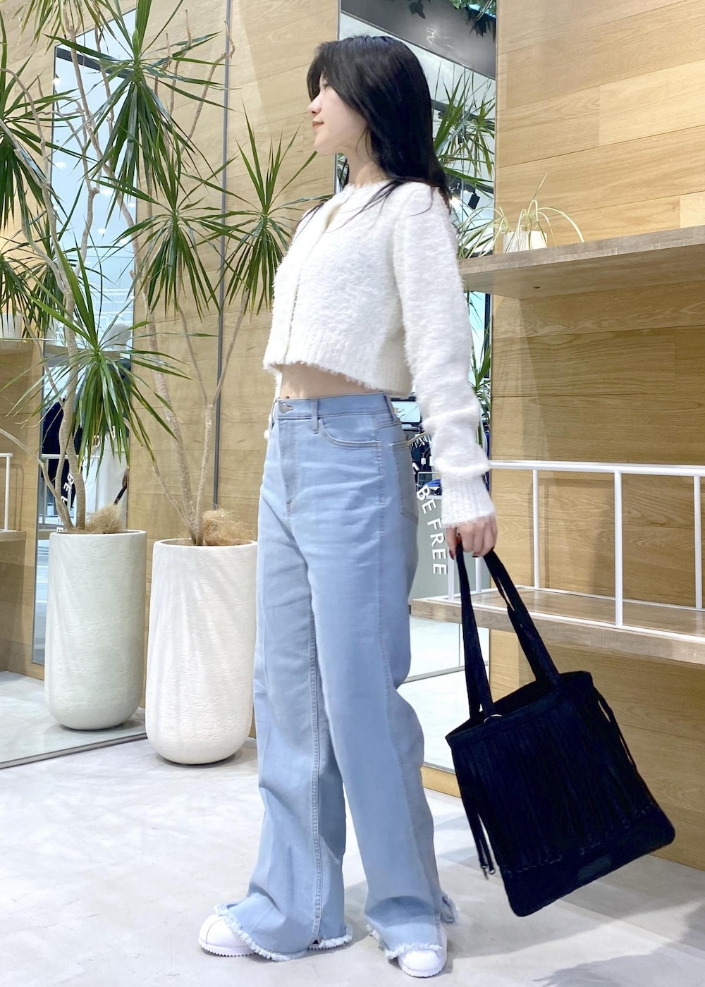 ホワイト系のスニーカー、ブルー系のデニムパンツ、ブラック系のトートバッグを着用したレディースの秋コーディネートの3枚目の写真