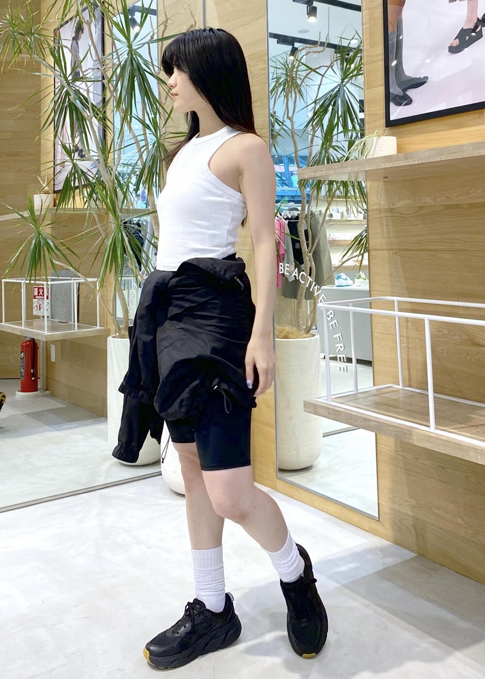 ブラック系のブルゾン、ホワイト系のタンクトップ、ブラック系のスニーカーを着用したレディースの夏コーディネートの6枚目の写真