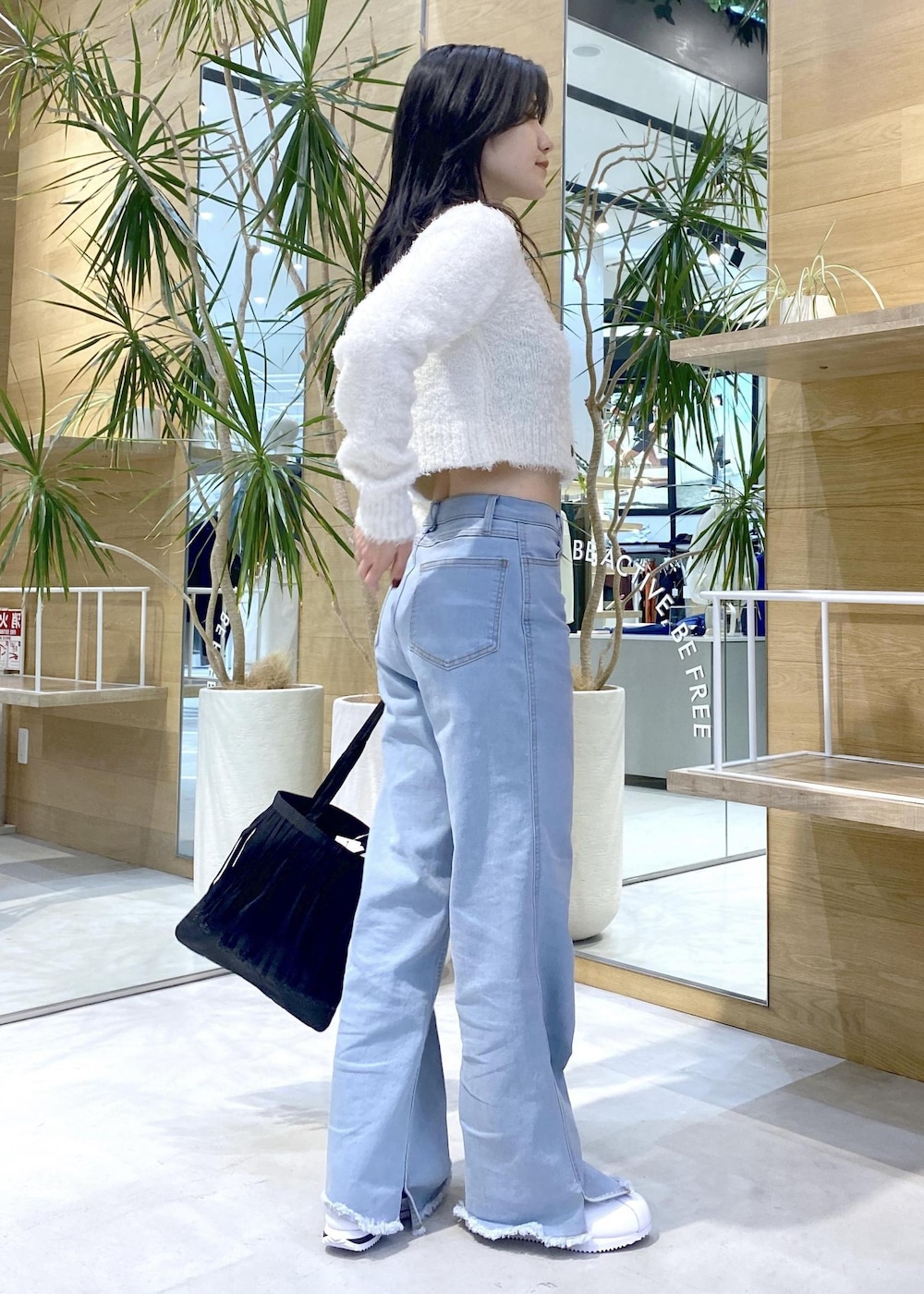 ホワイト系のスニーカー、ブルー系のデニムパンツ、ブラック系のトートバッグを着用したレディースの秋コーディネートの6枚目の写真