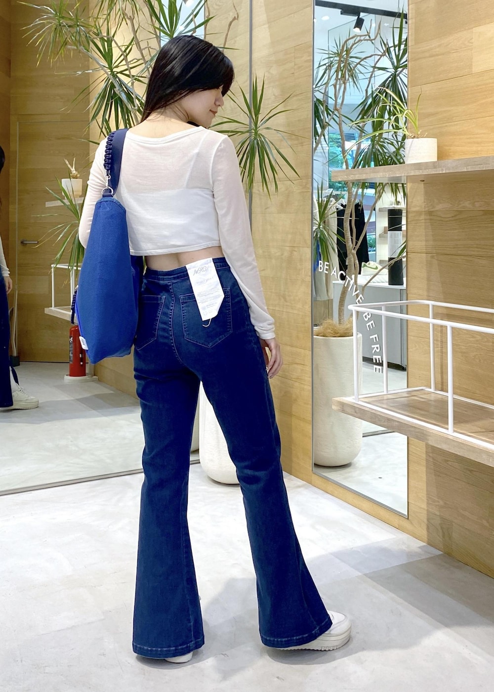 ホワイト系のスニーカー、ブルー系のデニムパンツ、ブルー系のトートバッグを着用したレディースの秋コーディネートの5枚目の写真