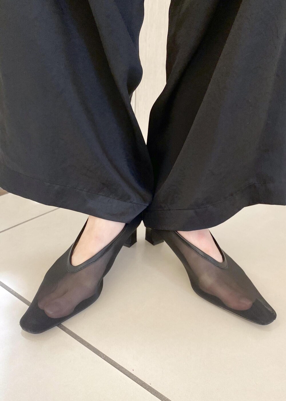 ブラック系のパンプス、ブラック系のスラックス、レッド系のハンドバッグを着用したレディースの夏コーディネートの9枚目の写真