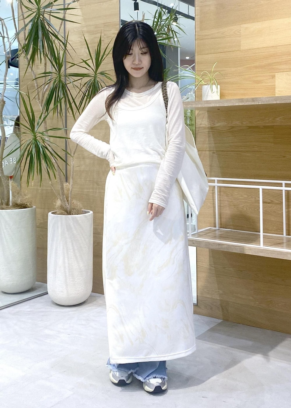 イエロー系のスカート、ホワイト系のアンサンブル、ブルー系のデニムパンツを着用したレディースの秋コーディネートの8枚目の写真