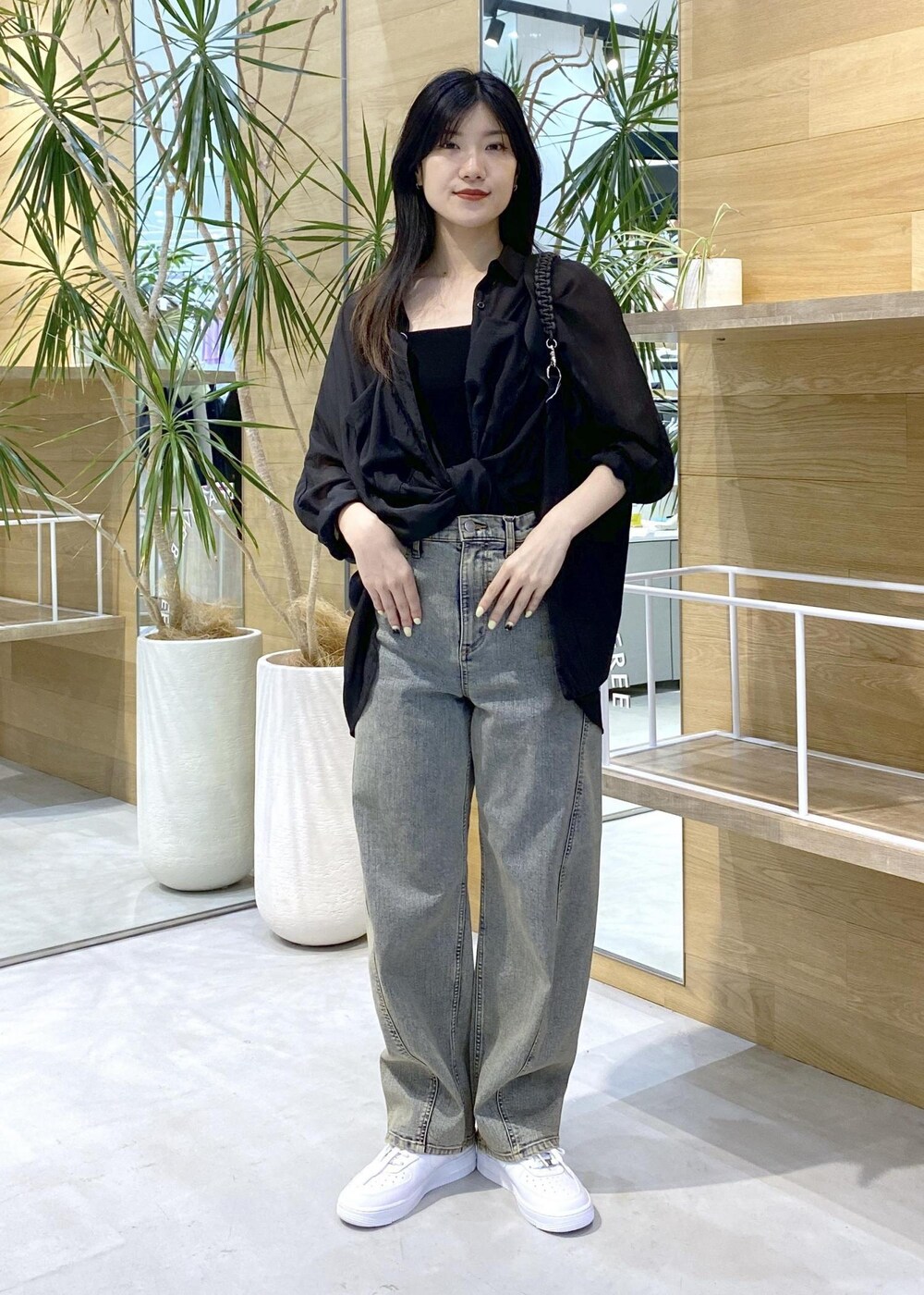 ホワイト系のスニーカー、ブラック系のキャミソール、ベージュ系のデニムパンツを着用したレディースの秋コーディネートの2枚目の写真