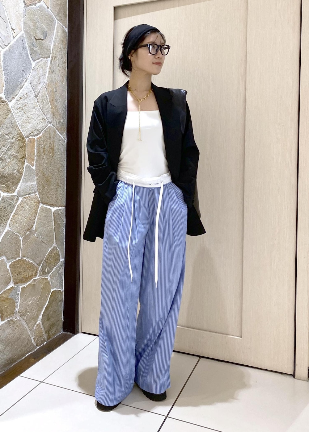 ブルー系のスラックス、ブラック系のテーラードジャケット、ブラック系のローファーを着用したレディースの秋コーディネートの2枚目の写真