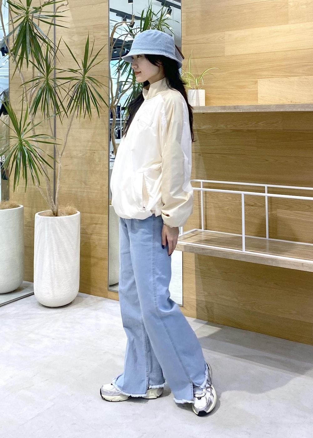 ホワイト系のスニーカー、ブルー系のデニムパンツ、ブルー系のハットを着用したレディースの秋コーディネートの4枚目の写真