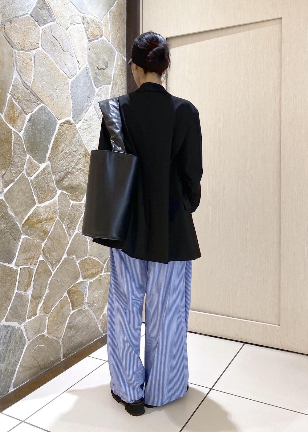 ブルー系のスラックス、ブラック系のテーラードジャケット、ブラック系のローファーを着用したレディースの秋コーディネートの4枚目の写真