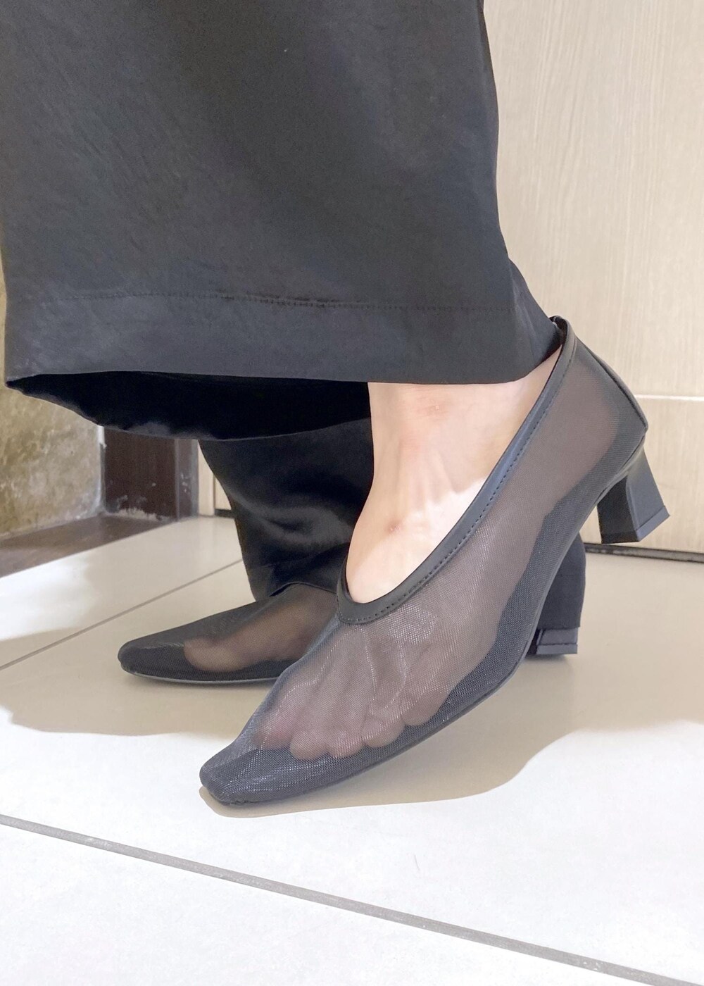 ブラック系のパンプス、ブラック系のスラックス、レッド系のハンドバッグを着用したレディースの夏コーディネートの8枚目の写真