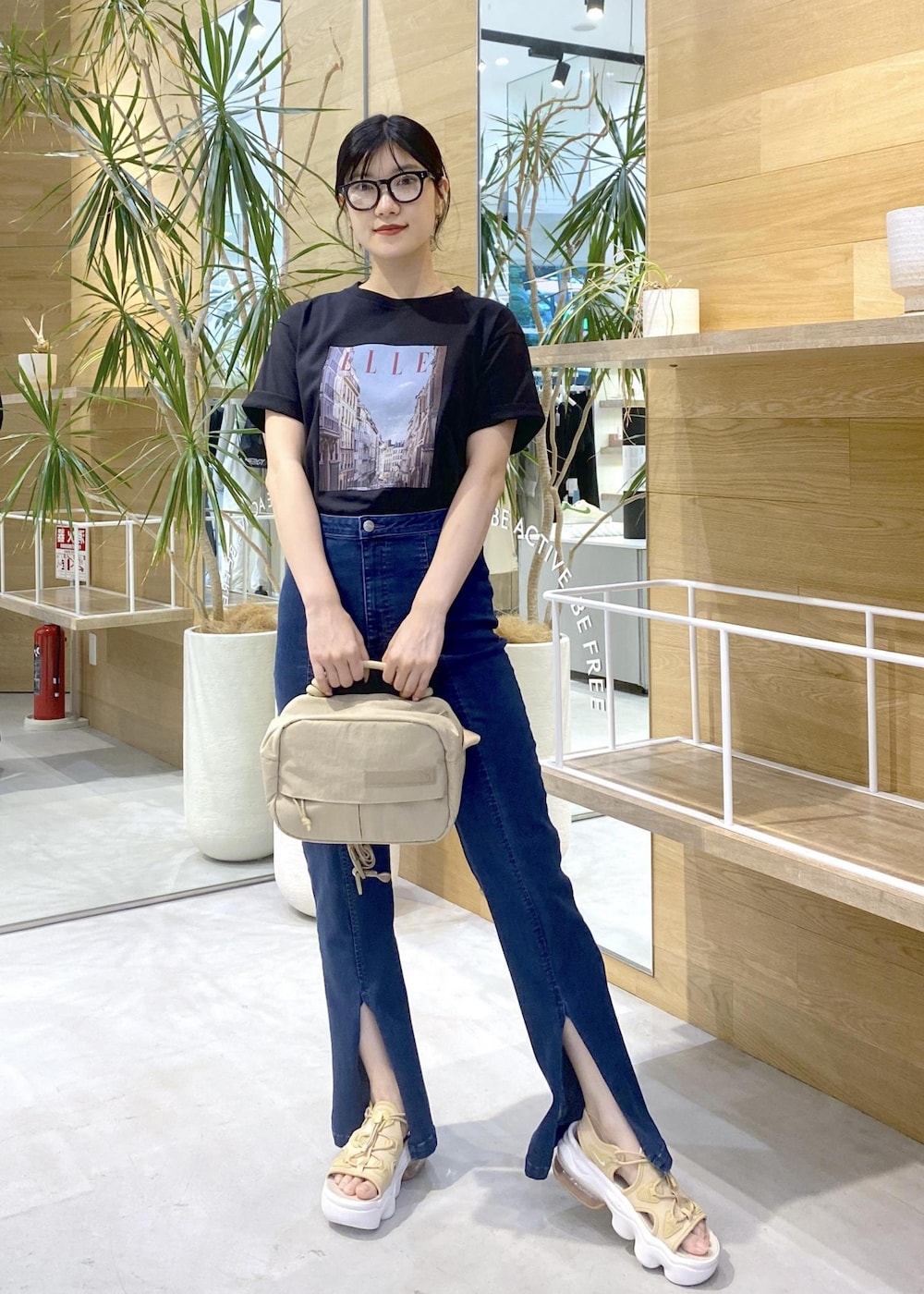 ブルー系のデニムパンツ、ベージュ系のサンダル、ブラック系のTシャツ/カットソーを着用したレディースの夏コーディネートの2枚目の写真