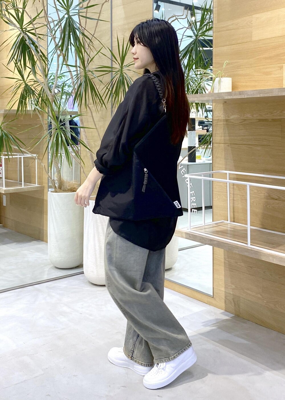 ホワイト系のスニーカー、ブラック系のキャミソール、ベージュ系のデニムパンツを着用したレディースの秋コーディネートの6枚目の写真