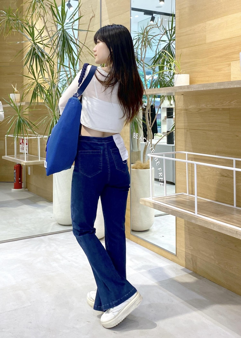 ホワイト系のスニーカー、ブルー系のデニムパンツ、ブルー系のトートバッグを着用したレディースの秋コーディネートの7枚目の写真