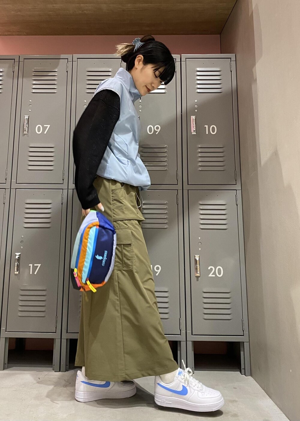 グリーン系のスカート、ブルー系のブルゾン、ブラック系のTシャツ/カットソーを着用したレディースの春コーディネートの2枚目の写真