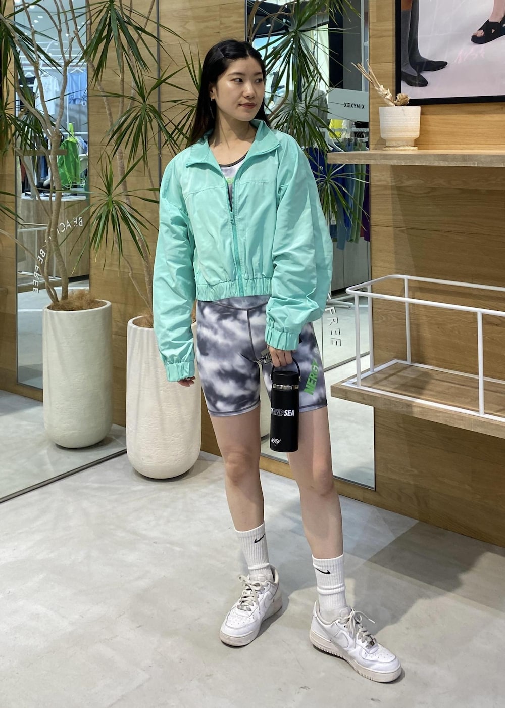 ホワイト系のスニーカー、グリーン系のナイロンジャケット、ブラック系のブラジャーを着用したレディースの春コーディネートの4枚目の写真