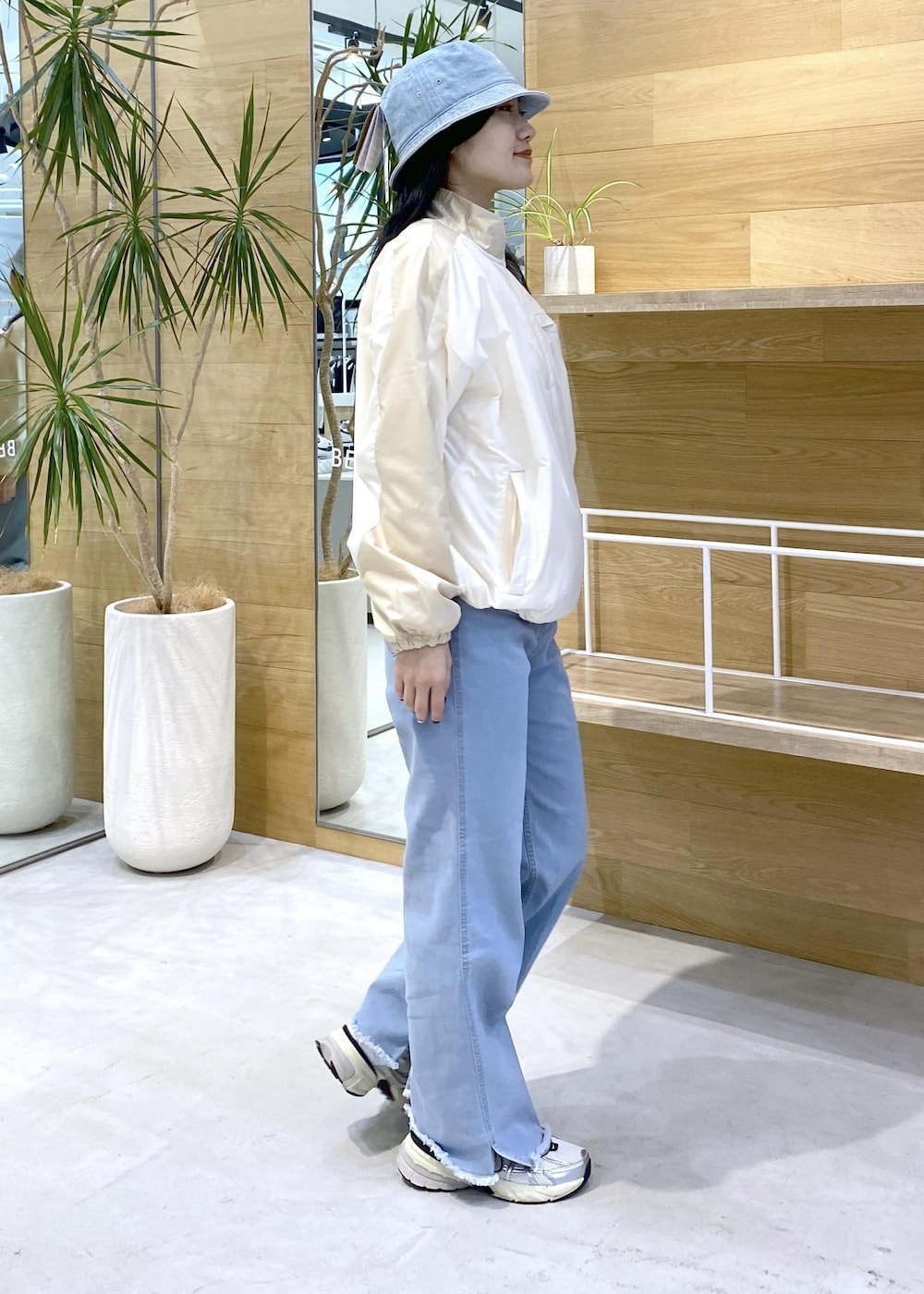 ホワイト系のスニーカー、ブルー系のデニムパンツ、ブルー系のハットを着用したレディースの秋コーディネートの6枚目の写真