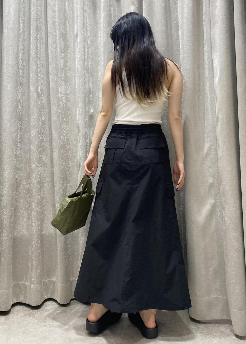 ブラック系のサンダル、ブラック系のスカート、ホワイト系のタンクトップを着用したレディースの春コーディネートの4枚目の写真