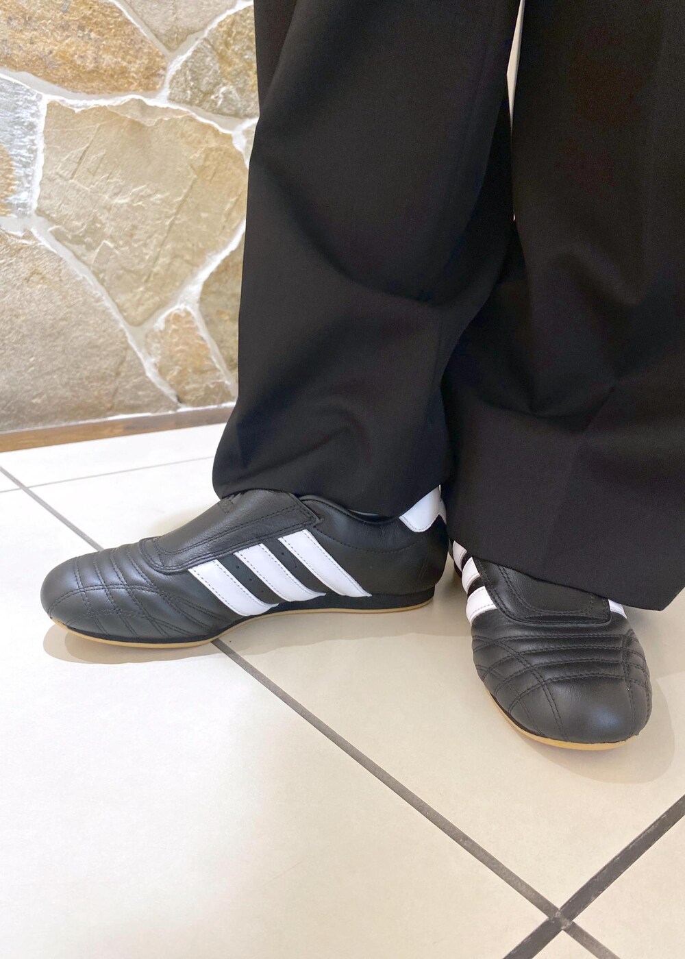 ブラック系のスニーカー、グレー系のニット/セーター、ブラック系のスラックスを着用したレディースの秋コーディネートの7枚目の写真