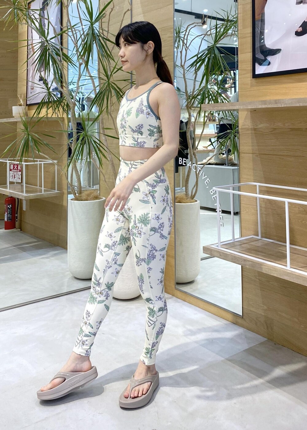 ベージュ系のサンダル、ホワイト系のラッシュガード、グリーン系のスポーツグッズを着用したレディースの夏コーディネートの5枚目の写真